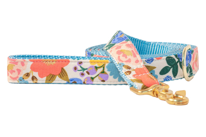 Colorful dog leash featuring a vibrant floral pattern against a light cream background. The leash is backed with bright nylon webbing for durability and contrast. A swivel clasp and D-ring add a polished, elegant finish.