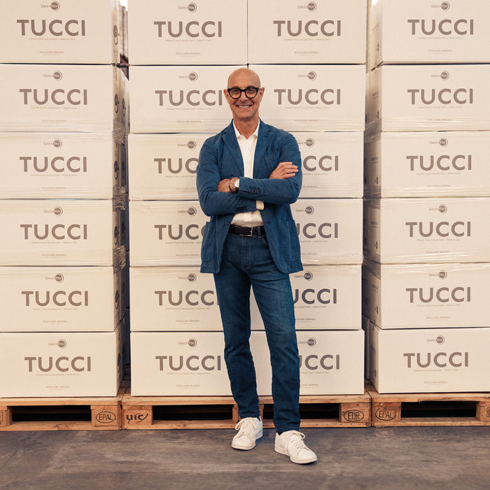 Man in glasses with arms crossed stands by Stanley Tucci 2-Quart Saucepan boxes stacked on wooden pallets.