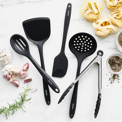 Black 5-piece silicone utensil set on white marble with pasta, garlic, rosemary, and spices.