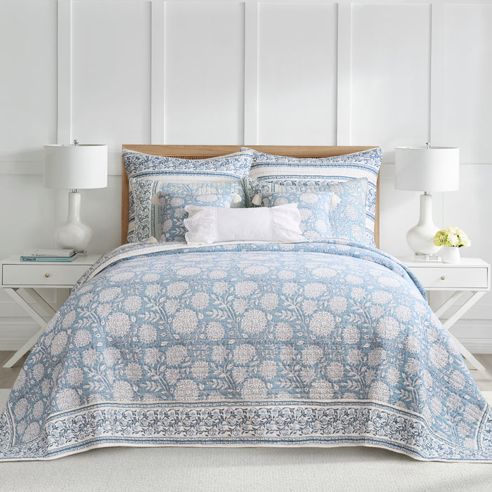 Bed with floral-patterned blue and white bedding in a bedroom setting.