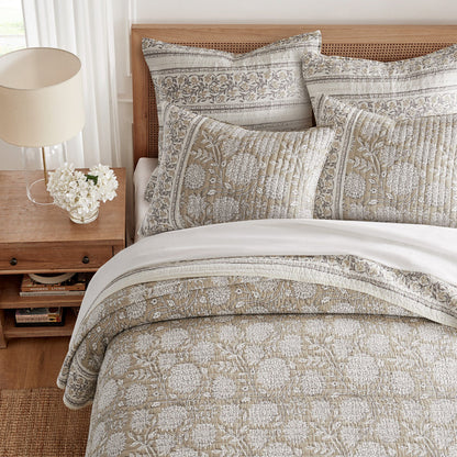 Bed with patterned bedding and pillows in a bedroom setting.