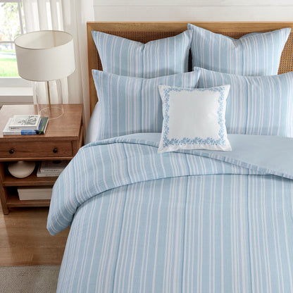 Boracay Stripe Muslin Duvet Cover Set displayed on a bed with blue striped pattern and decorative pillows.
