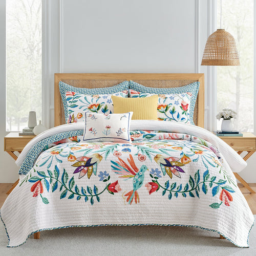 A colorful quilt featuring a variety of bird and floral prints