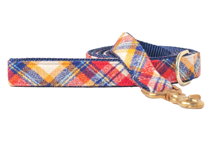 Plaid dog leash made with a soft flannel fabric in rich tones. The leash is shown coiled with a dark nylon underside and finished with polished hardware, giving it a cozy, seasonal look ideal for autumn walks.