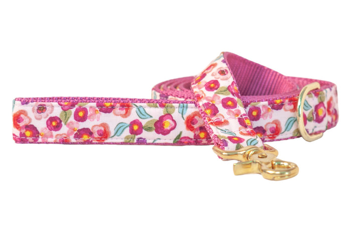 Dog leash with a vivid floral print featuring small flowers with leaves on a light background. The leash is backed with textured nylon webbing for strength and includes polished hardware, including a swivel snap hook and D-ring.
