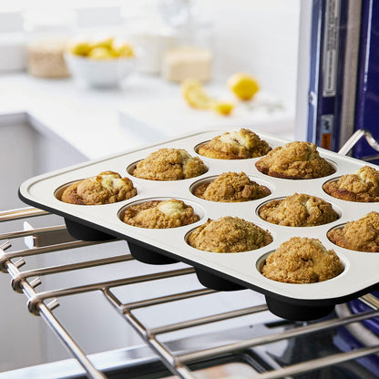 GreenLife green ceramic nonstick muffin pan with nine baked muffins on a kitchen counter.