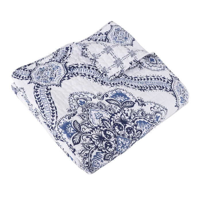 Lentana Navy Quilted Throw featuring intricate medallion pattern in navy and white, perfect for cozying up on the couch.