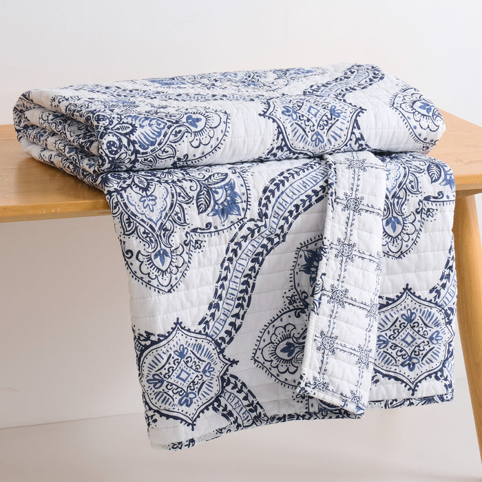 Lentana Navy Quilted Throw displayed on a wooden table, showcasing its intricate medallion pattern and soft cotton fabric.