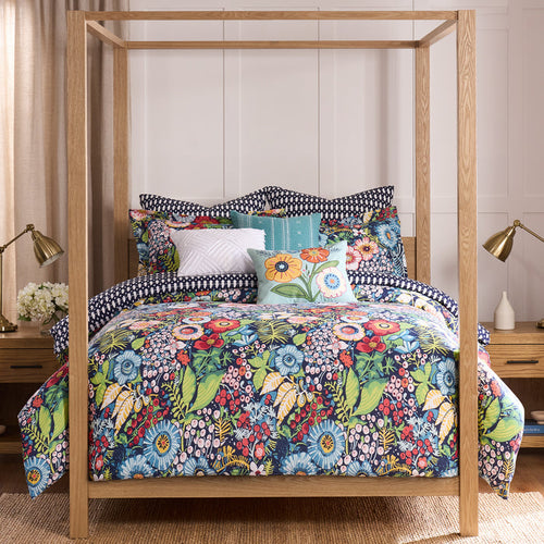 Floral bedding set on a wooden bed with matching pillows in a bedroom setting.