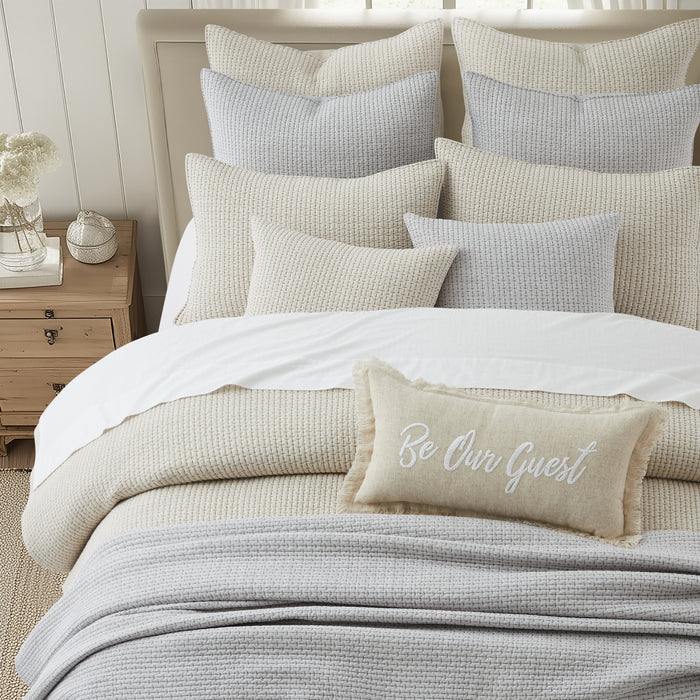 Cozy bedroom setup featuring Pick-Stitch Artisan Square Pillow with various textured pillows on a stylish bed.