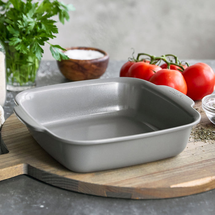 Gray ceramic 8x8 square baker with built-in handles, shown on a kitchen counter.