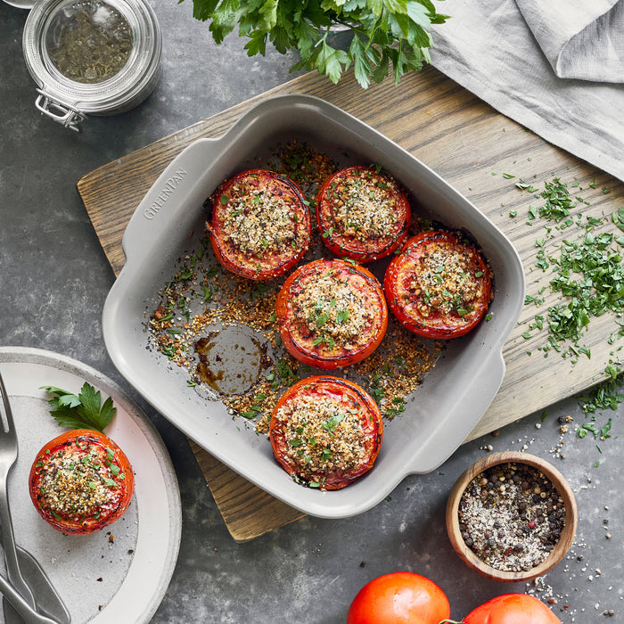 Stuffed tomatoes in a white ceramic nonstick 8x8 inch square baker, topped with chopped parsley.