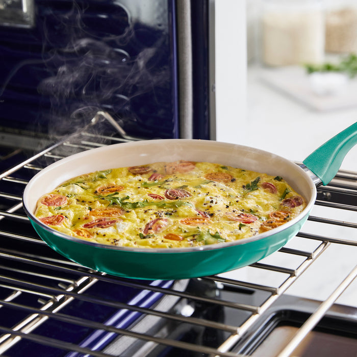 A turquoise Rio Ceramic Nonstick 8" Frypan with Spatula holds a steaming vegetable frittata with tomatoes, herbs, and cheese on an open oven rack.