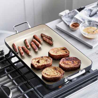 Sausages and French toast cooking on a black Rio Double Griddle with ingredients beside the griddle.