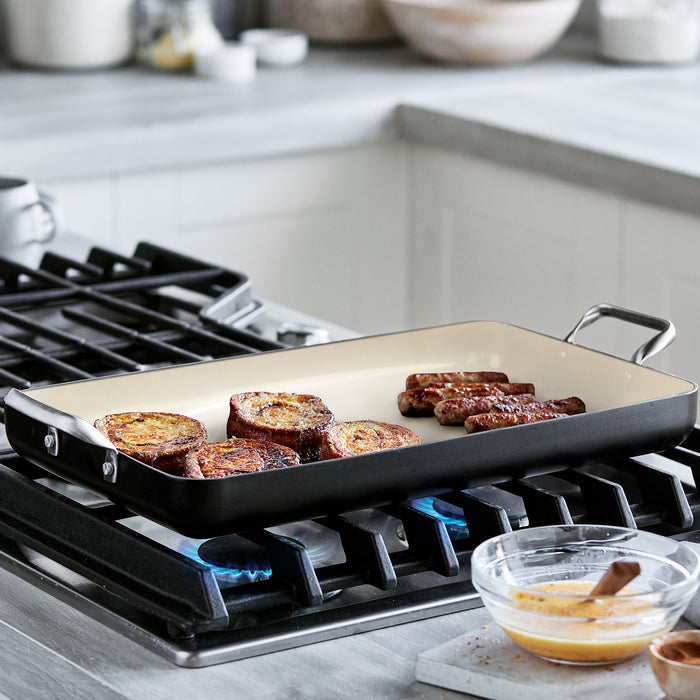 Black Rio double griddle on stovetop with sausage links; bowl of whisked eggs beside it.