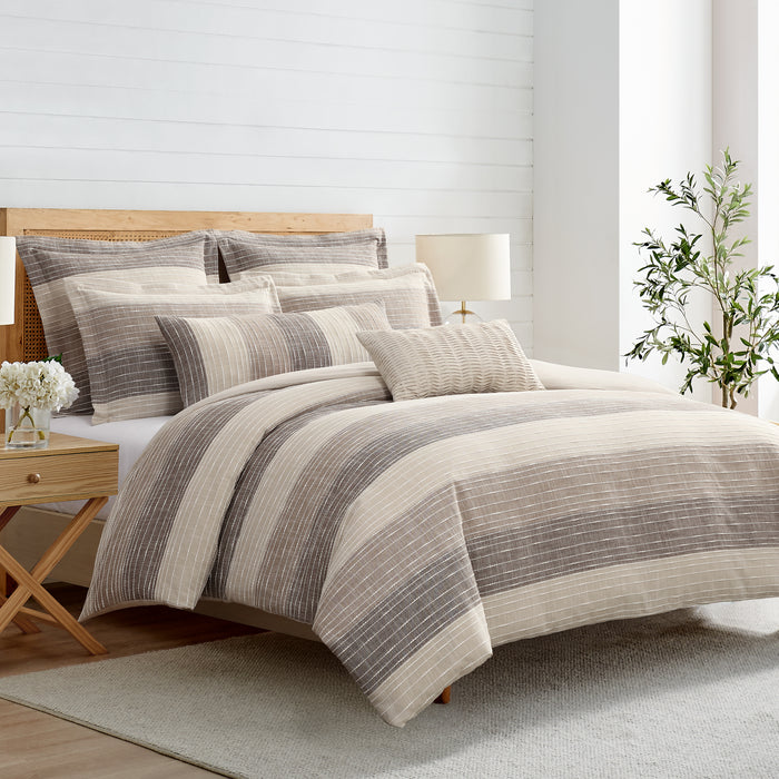 Neatly made bed with striped bedding in a bedroom setting.