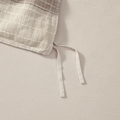 Close-up of a beige fabric with a textured edge on a light background