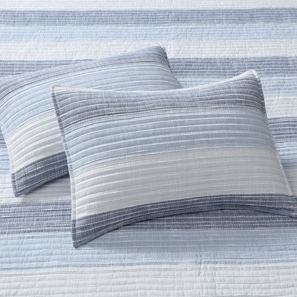 Sand Stripes Blue Quilt with two textured pillows in shades of blue and white, showcasing coastal-inspired design.
