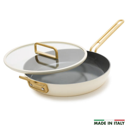 White ceramic nonstick 12-inch frypan with gold handle and glass lid.