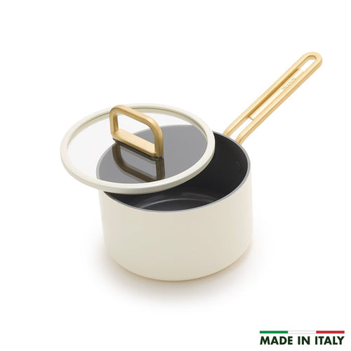 White ceramic nonstick saucepan with gold handle and glass lid, 2-quart size, shown at an angle.