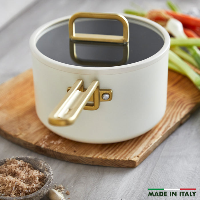 White 4-quart saucepan with gold handles and lid, Carrara finish, MADE IN ITALY label visible.