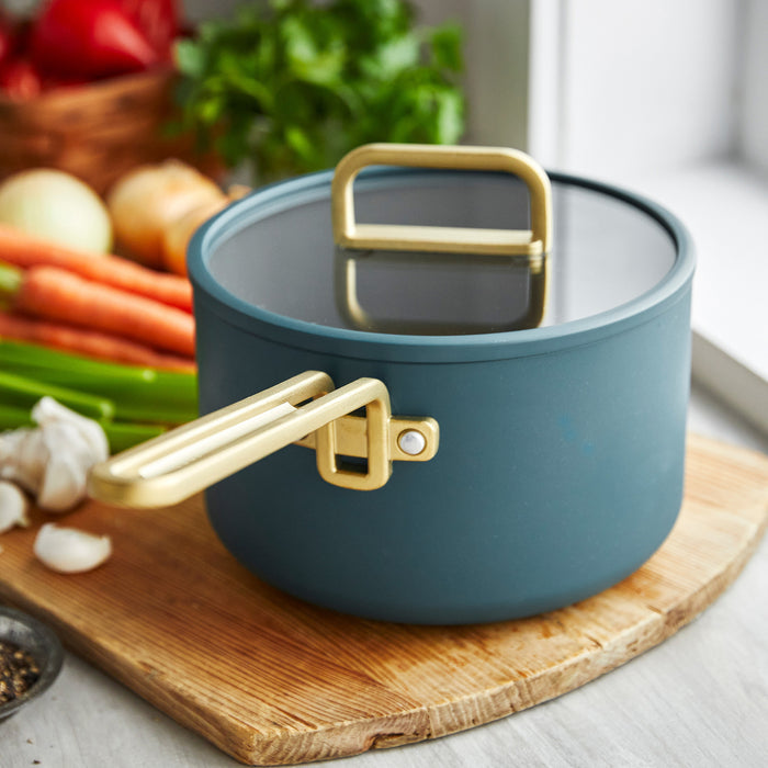 Venetian teal ceramic nonstick 4-piece saucepan set displayed next to assorted fresh vegetables.