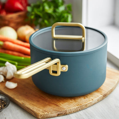 Venetian teal ceramic nonstick 4-piece saucepan set displayed next to assorted fresh vegetables.