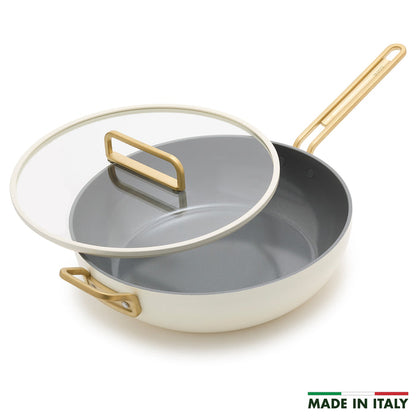 White ceramic 6.5-quart pan with gold handles and a glass lid.