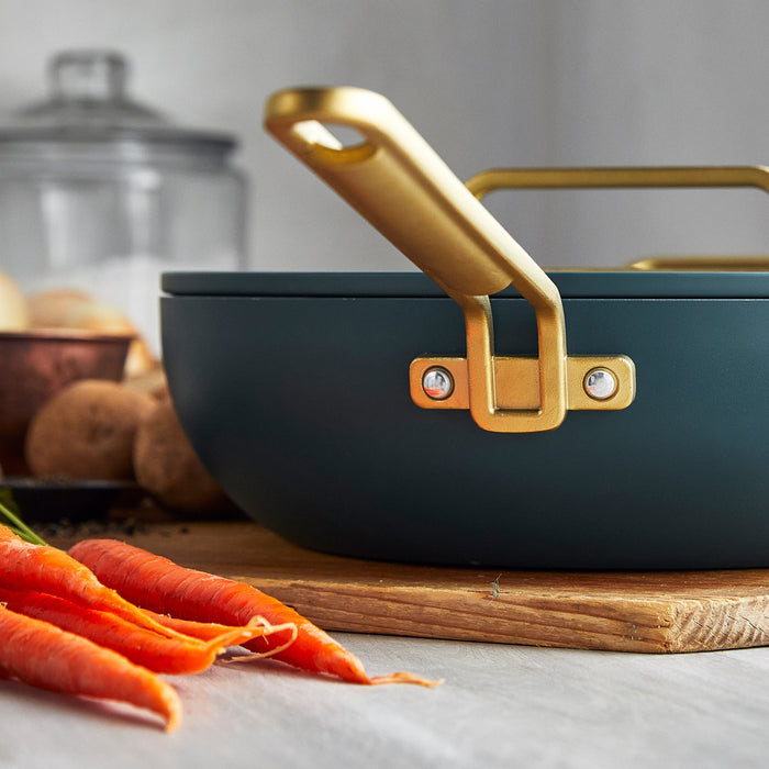 Venetian teal ceramic nonstick 6.5-quart pan on wood surface, fresh carrots placed beside it.