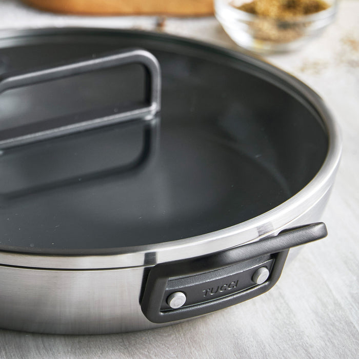 Stanley Tucci 12-inch stainless steel frypan with black handle and matching lid shown on a countertop.
