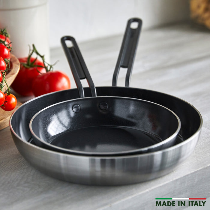 Set of two black-handled nonstick frypans, 8-inch and 10-inch, nested on a counter; Made in Italy text visible.
