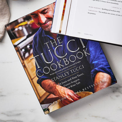 The Tucci Cookbook next to an open book on a flat surface, both books showing pages.