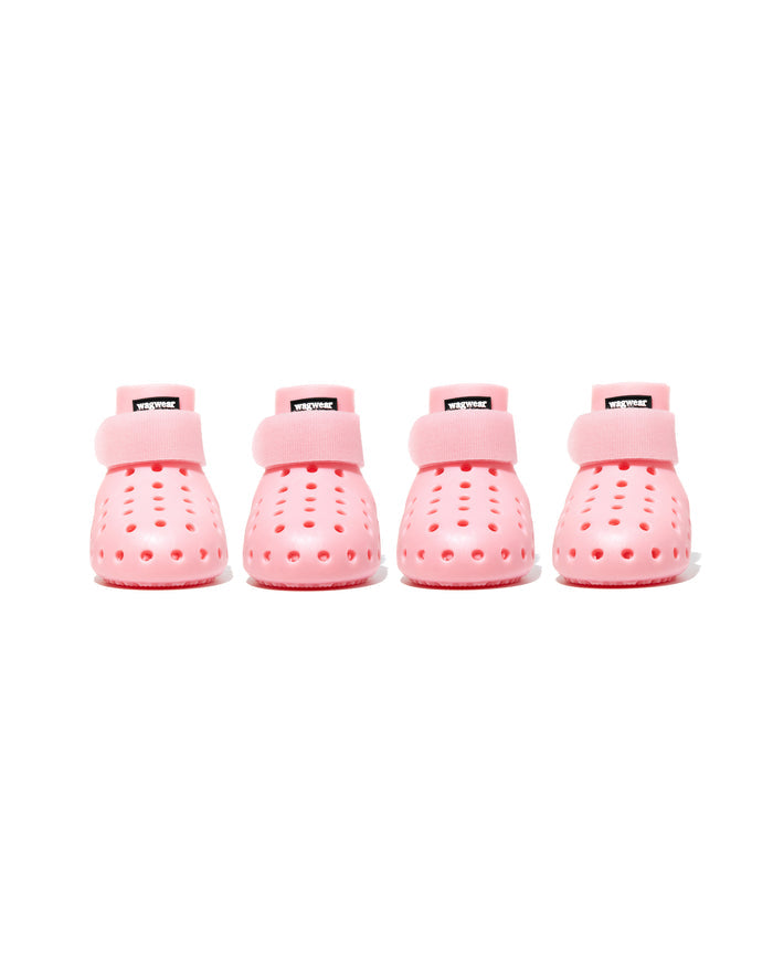 Four pink dog boots with a strap on a white background