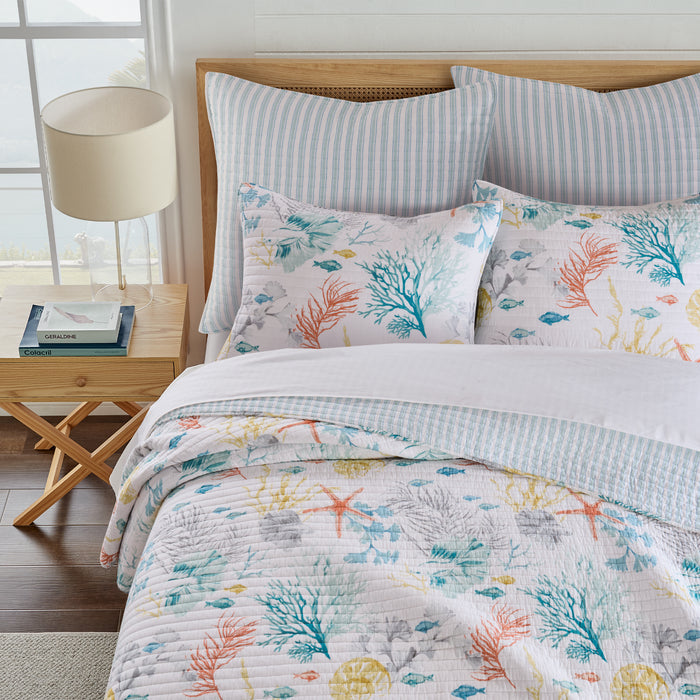 Bed with floral bedding and pillows in a bright room