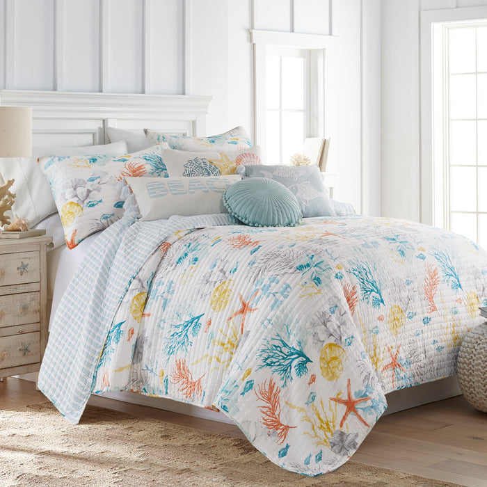 Bed with colorful floral quilt and pillows in a bright bedroom.