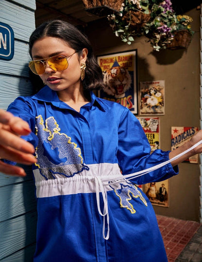 Wild Royal Blue Shirt Dress with abstract blue and yellow embroidery, contrasting white drawstring waist panel, and three-quarter sleeves in a chic relaxed silhouette.