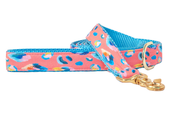 A bold dog leash with a coral pink base and abstract leopard spots, finished with a bright nylon lining and polished hardware.